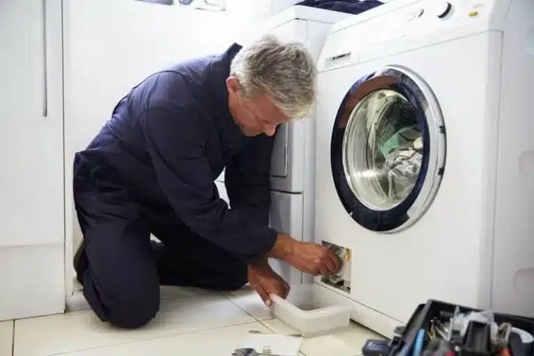 Tecnico arreglando una lavadora que no desagua